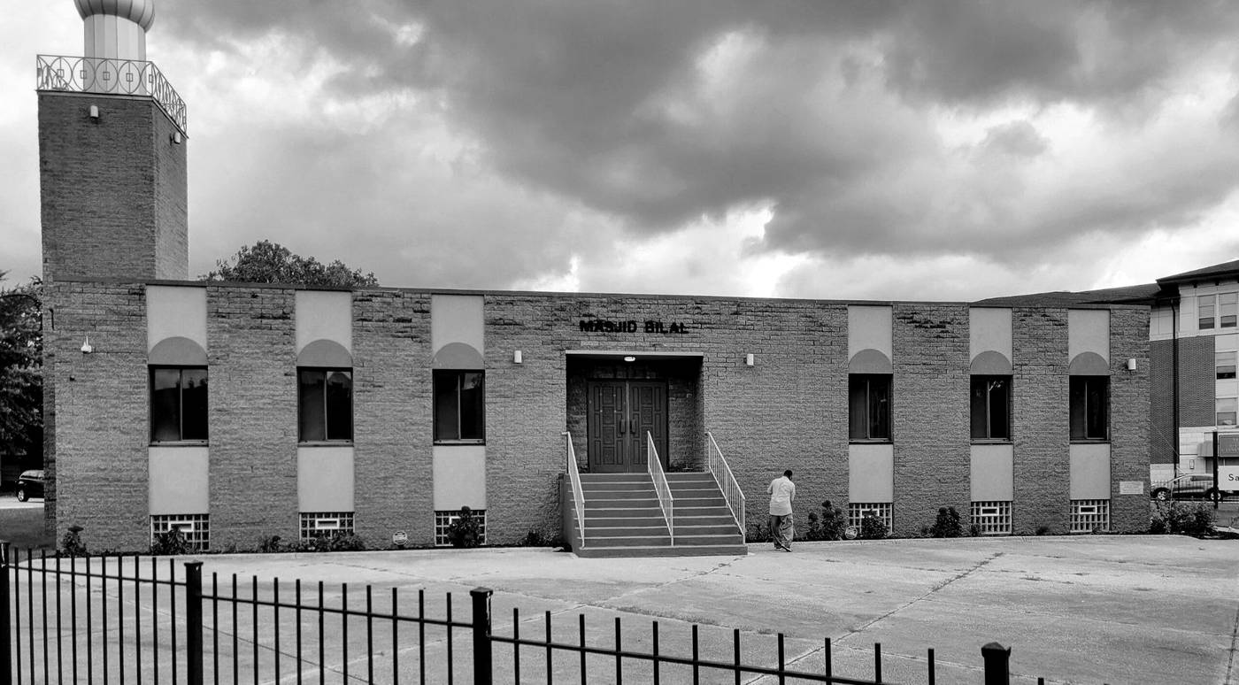The front of Masjid Bilal on Euclid Avenue: a long brick building with arched panels over the windows, red front doors up a flight of steps, and the minaret at the left corner.